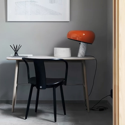 Stylish post-modern marble desk lamp with orange shade on a minimalist desk in a contemporary setting.