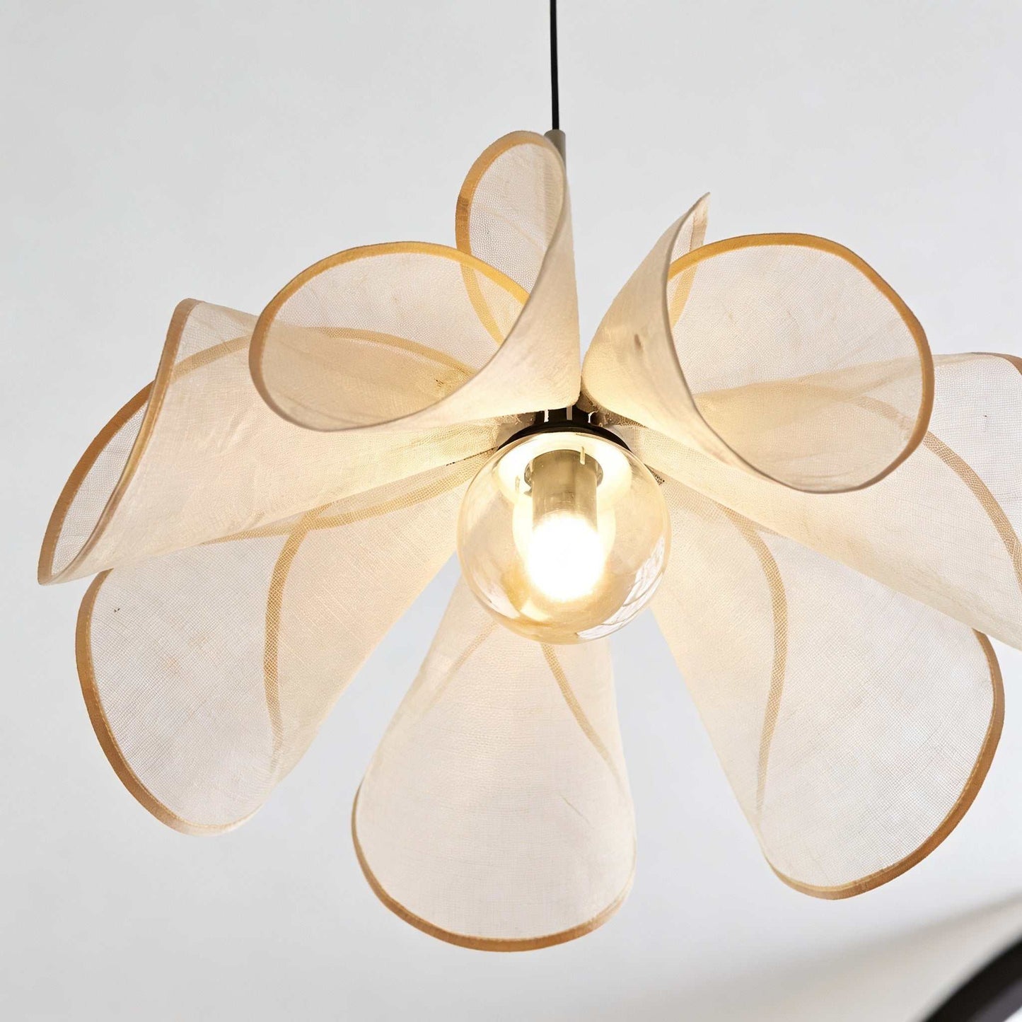 Petal Pendant Light with branch-shaped rattan shade casting warm ambient glow in cozy boho room