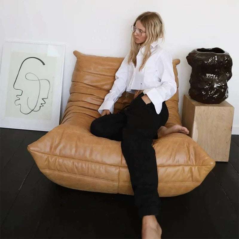Togo Chair Dupe in fiber leather with person sitting, designed by Michel Ducaroy, showcasing ergonomic comfort and style.