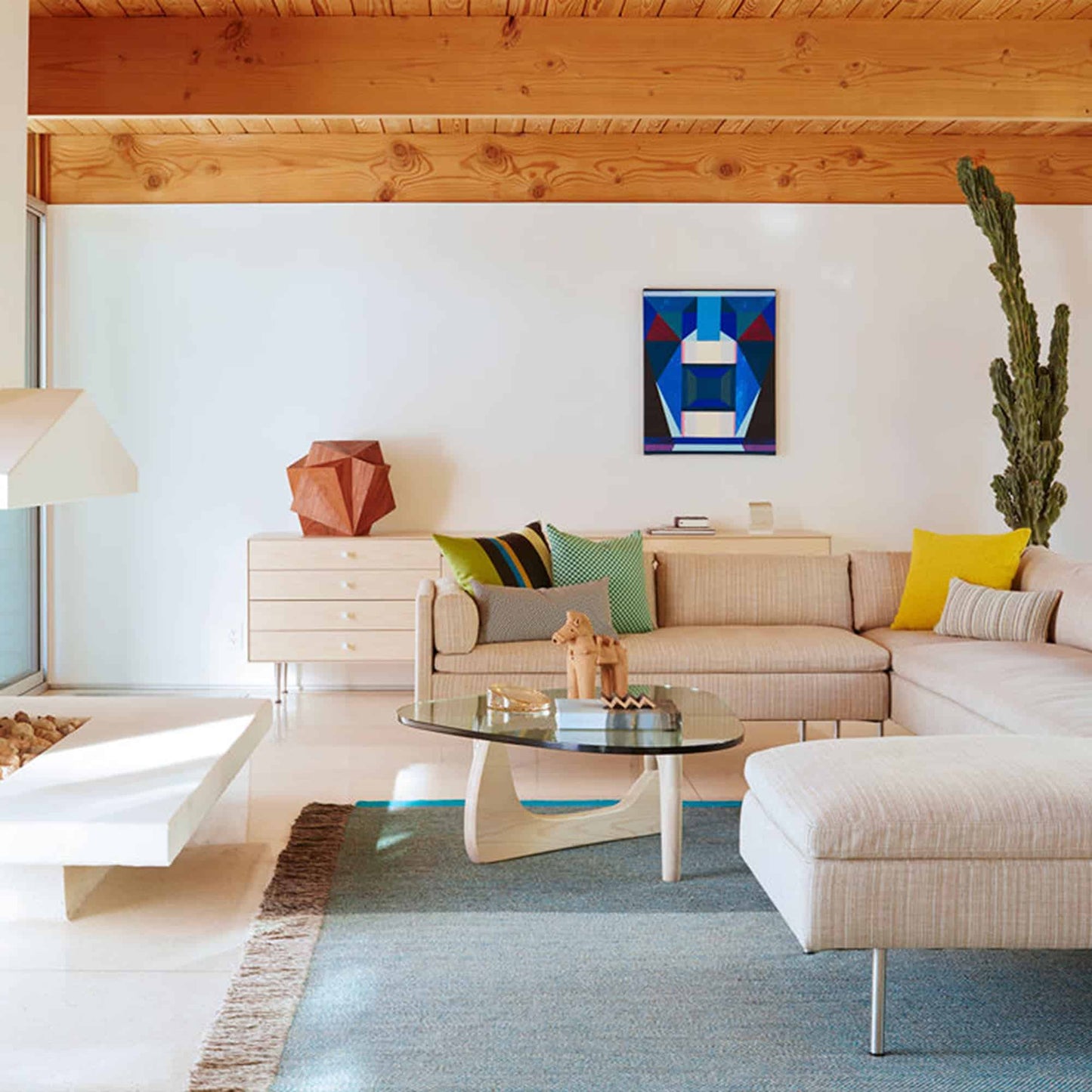 Noguchi Coffee Table in modern living room setting with sculptural wood base and glass top.