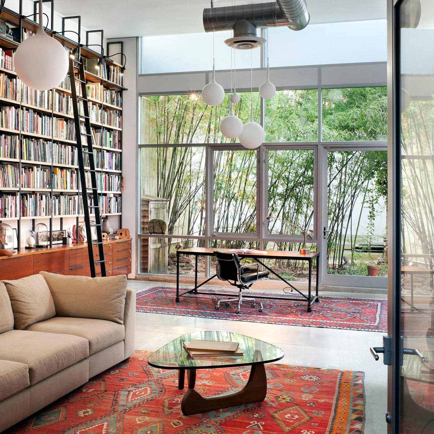 Noguchi Coffee Table in modern living space with bookshelf and large windows.