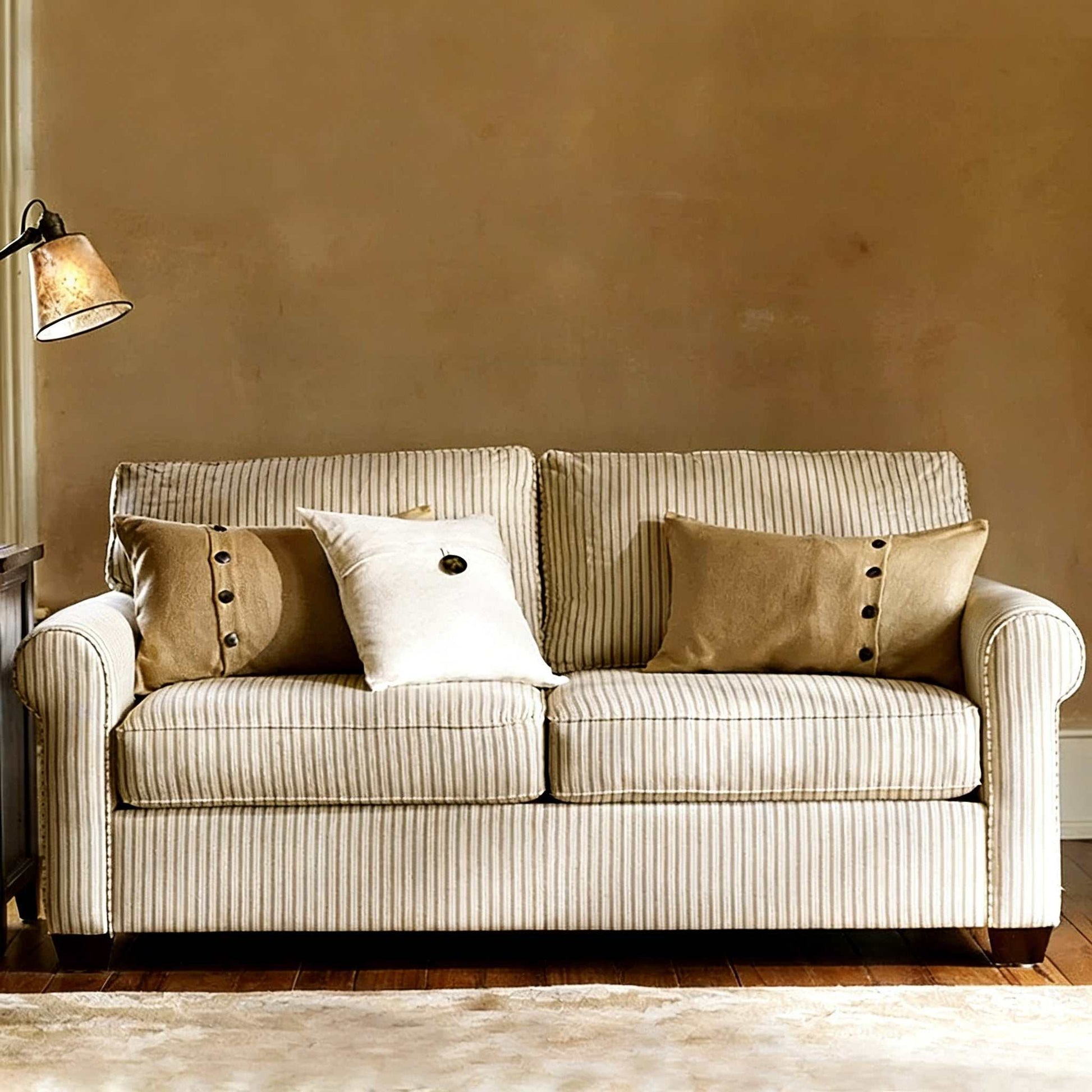 Striped fabric sofa with decorative pillows in a room with a lamp and beige wall.
